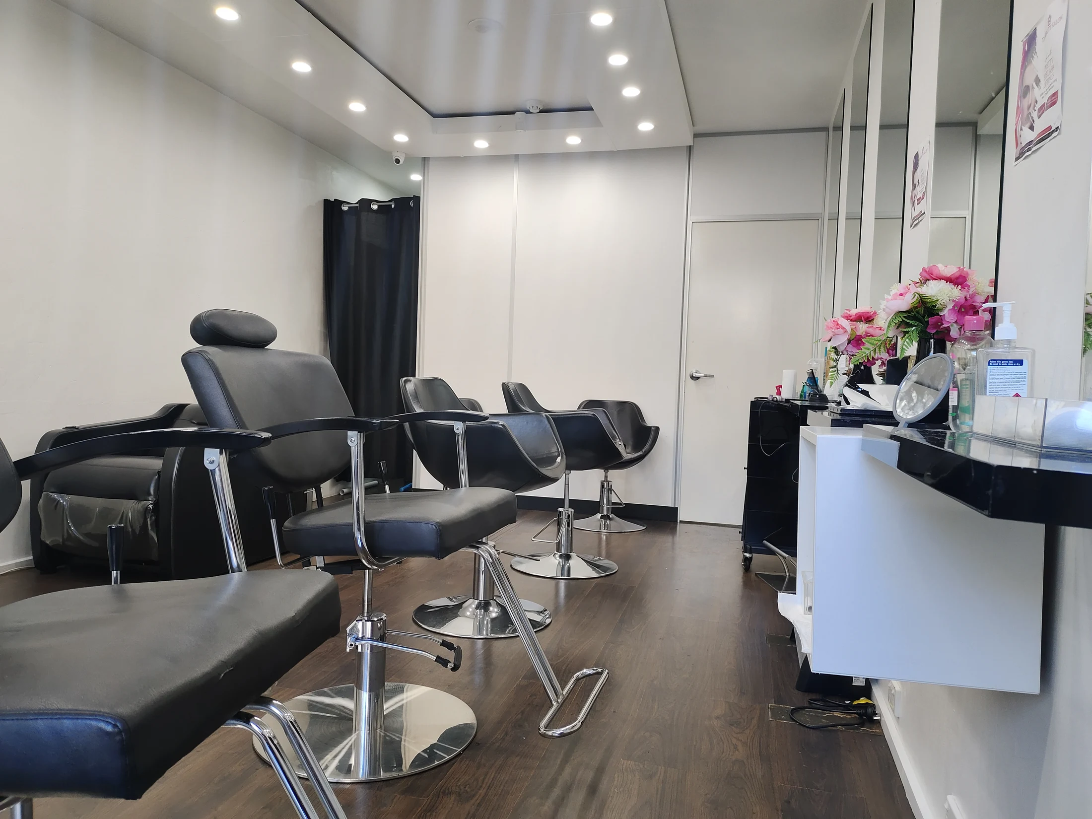 The salon floor &mdash; reclining treatment chair, three styling stations and mirror bank