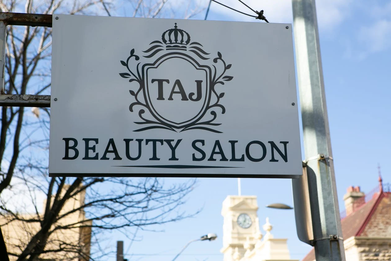 The projecting Taj Beauty Salon crest sign against blue sky